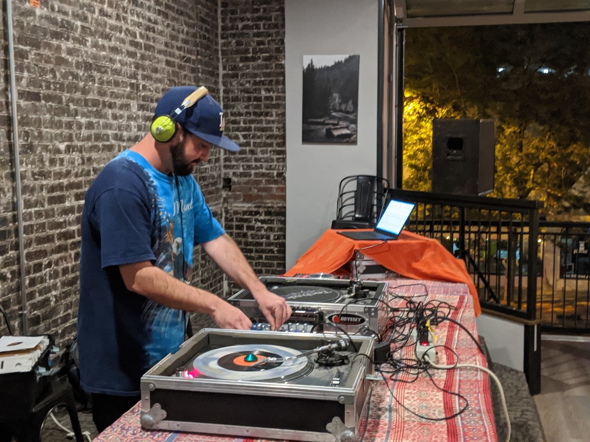 Casey Green mixing on turntables against a brick wall
